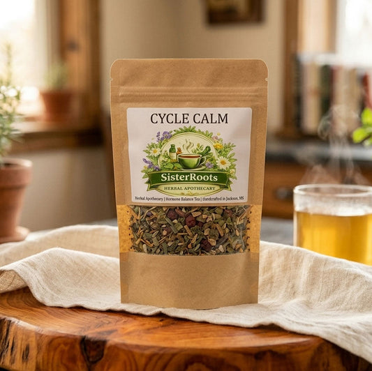 Sister Roots Cycle Calm tea package on a light-colored wooden table next to a soft linen kitchen napkin, styled in a warm, comforting home environment.