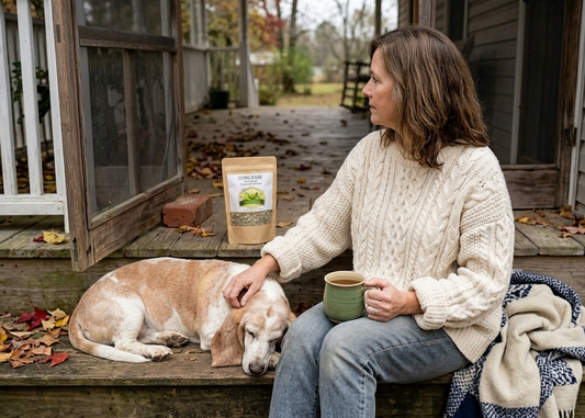 Woman drinking Sister Roots Lung Ease herbal tea on porch with dog